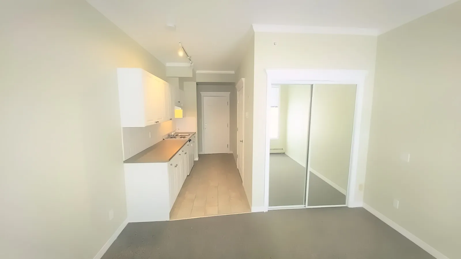 An empty suite ready for a tenant, with a kitchenette and mirrored closet